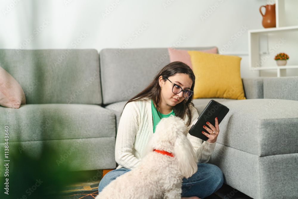 Young woman reading e-book on tablet with pet dog at home Young woman reading e-book on tablet with pet dog at home