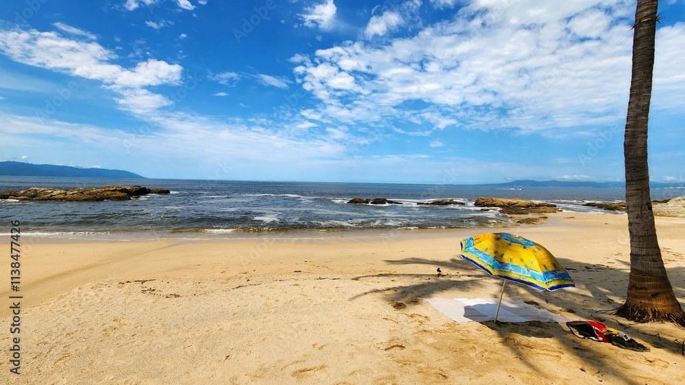 Relaxing beach day with bright umbrella and gentle waves near a tropical coastline Relaxing beach day with bright umbrella and gentle waves near a tropical coastline