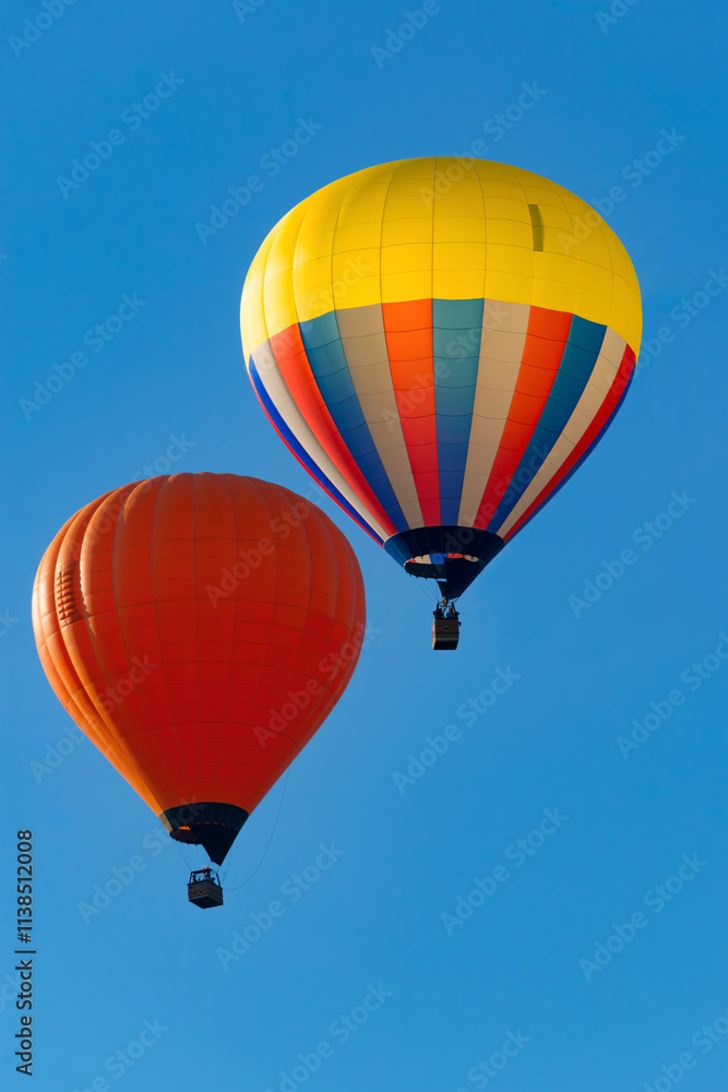 Naklejka premium 2 colorful hot-air balloons fly close together shortly after take-off at the Montgolfiade in Warstein, Sauerland. Pilots use gas flames and wind directions to steer the balloons at different heights.