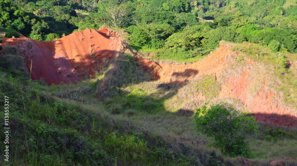 Obraz premium Padza de Mayotte. collines de terre rouge formées par l'érosion. la terre a différentes couleurs, rouge, orange, violet, rose, ocre, marron. village d'acoua dans le nord de l'ile