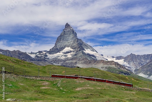 Red train passing Swiss mountains on Matterhorn mountain range background