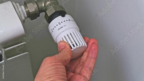 Hands adjusting modern radiator thermostat at home