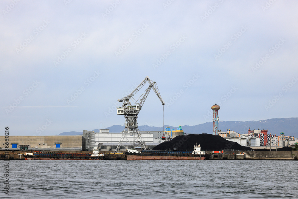 Large crane works on large coal stockpile at Osaka port. Large crane works on large coal stockpile at Osaka port.