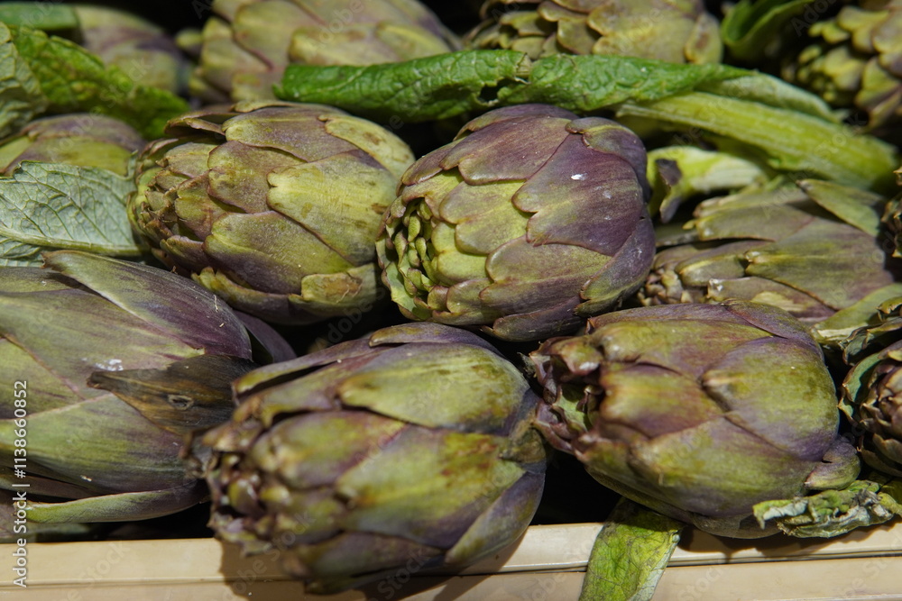 Fototapeta premium Fresh purple artichokes. Violet hues and intricate textures of tightly packed leaves with subtle green accents. Artichokes are arranged close together to create an organic pattern.