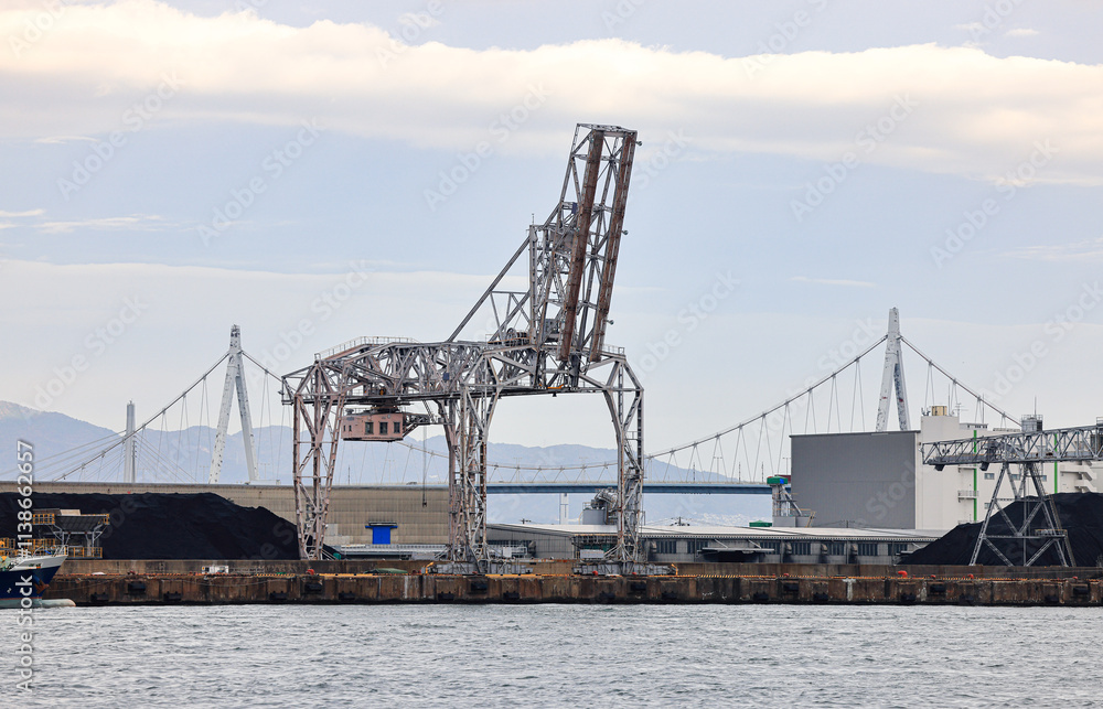 Large crane works on large coal stockpile at Osaka port. Large crane works on large coal stockpile at Osaka port.