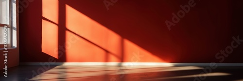 An empty room with a bright red wall bathed in sunlight, showcasing geometric shadows from a window.