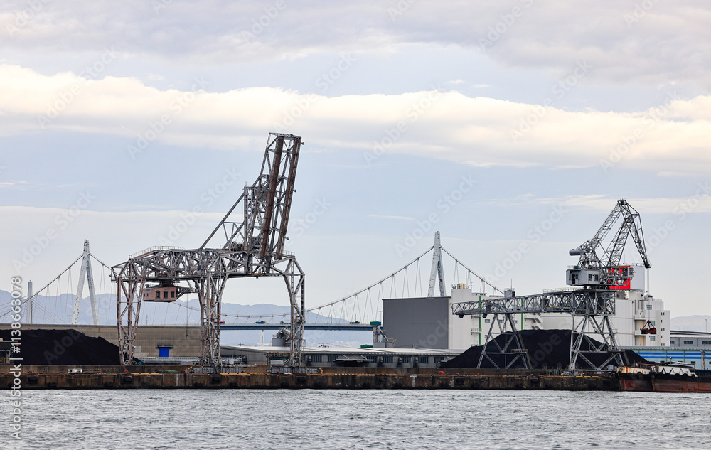 Large crane works on large coal stockpile at Osaka port. Large crane works on large coal stockpile at Osaka port.