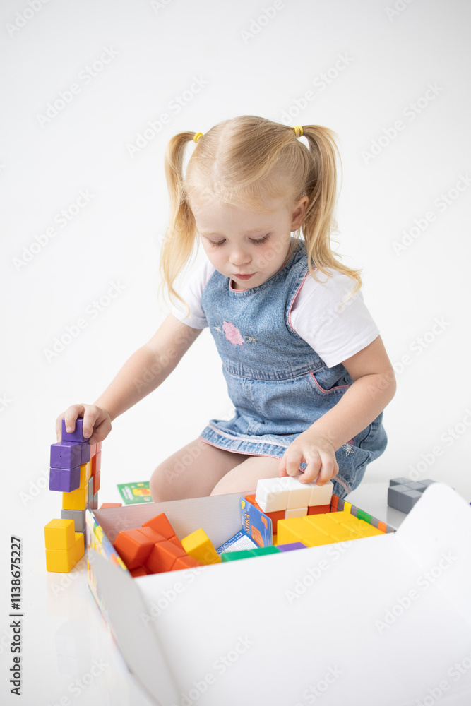 Educational Toys: The Child Develops Motor Skills With The Help Of Colorful Cubes on a white background. The girl is playing with cubes Educational Toys: The Child Develops Motor Skills With The Help Of Colorful Cubes on a white background. The girl is playing with cubes