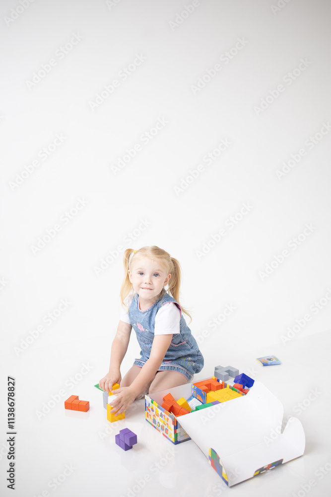 Educational Toys: The Child Develops Motor Skills With The Help Of Colorful Cubes on a white background. The girl is playing with cubes Educational Toys: The Child Develops Motor Skills With The Help Of Colorful Cubes on a white background. The girl is playing with cubes