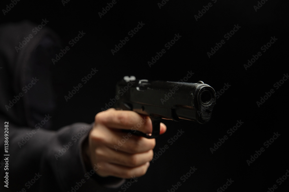 Hand holding a gun closeup, armed man on dark background. Danger and crime Hand holding a gun closeup, armed man on dark background. Danger and crime