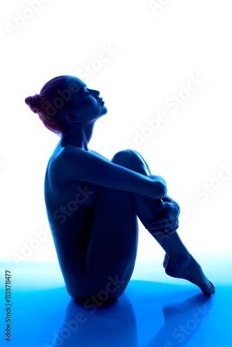 Cuadro en lienzo Silhouette of a woman sitting gracefully with blue lighting backdrop