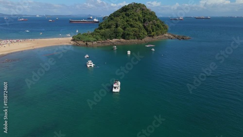 Aerial views of the beach on a sunny day of the island of Taboga in Panama, in the background the ships at the entrance of the Panama Canal.