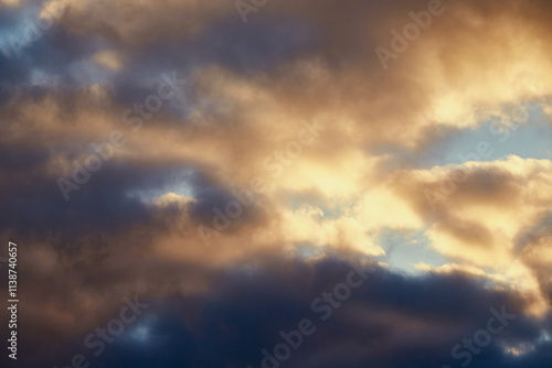 Calm winter sky with gray clouds softly lit by golden sunlight.