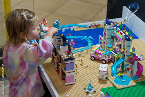 Happy girl child plays with various toys, construction sets, doll houses in the game center. Educational games - intellectual leisure for a child. Concept of the development of creativity.