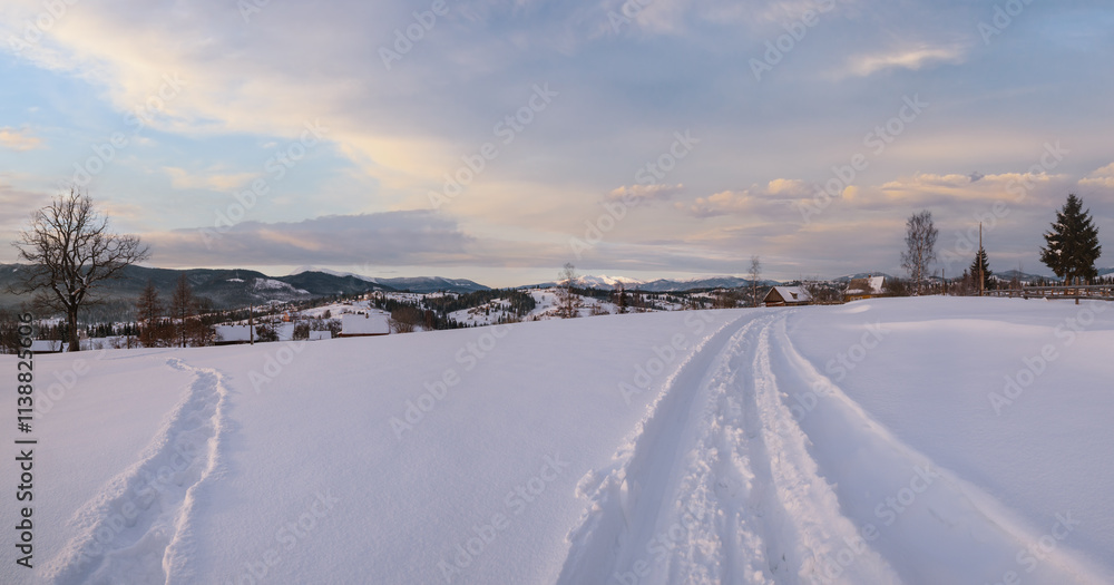 Small alpine village and winter snowy mountains in first sunrise sunlight around, Voronenko, Carpathian, Ukraine. Trace on freshly trodden path through snow drifts. Small alpine village and winter snowy mountains in first sunrise sunlight around, Voronenko, Carpathian, Ukraine. Trace on freshly trodden path through snow drifts.