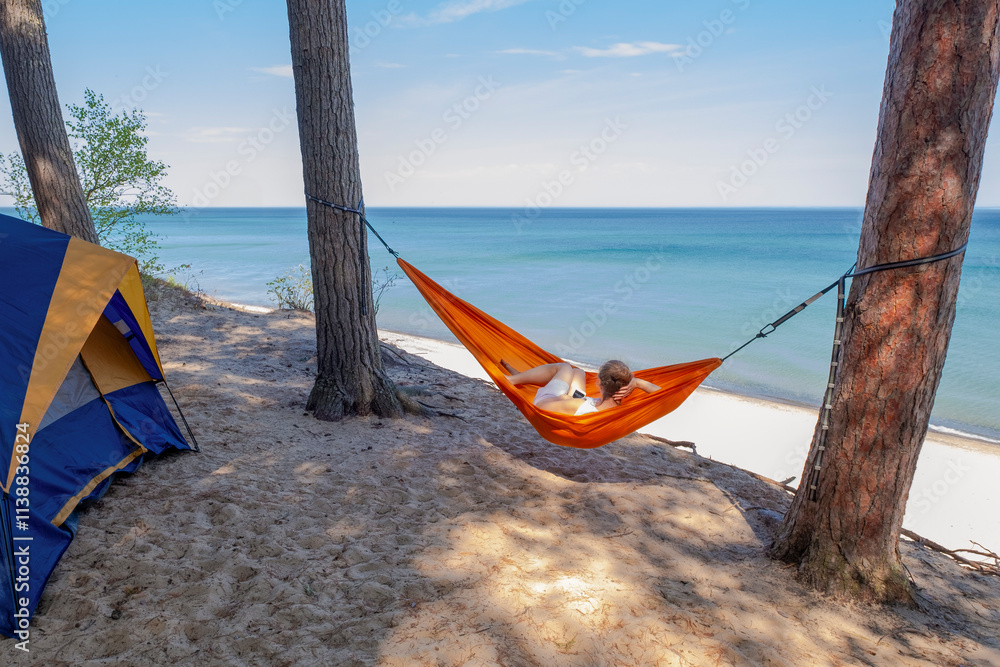 Woman in hammock observes Lake Superior from her camping site on a cliff