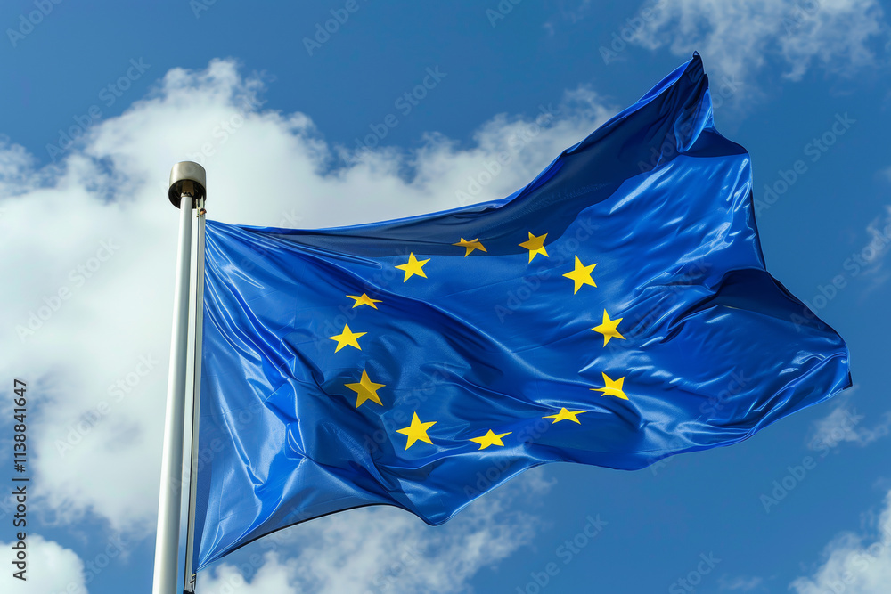 The blue national flag of European Union with twelve golden stars flutters in the wind in the blue sky The blue national flag of European Union with twelve golden stars flutters in the wind in the blue sky