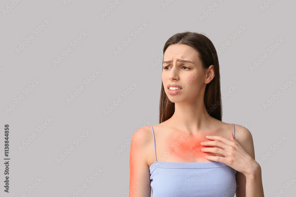 Young woman with red sunburned skin on grey background Young woman with red sunburned skin on grey background