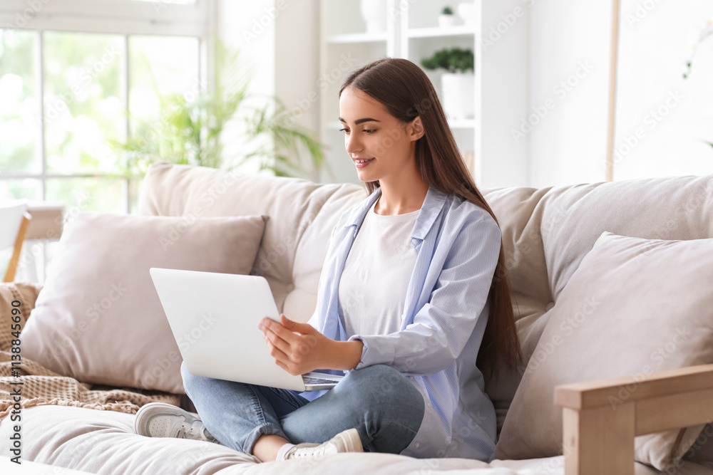 Beautiful young happy woman with laptop sitting on sofa at home Beautiful young happy woman with laptop sitting on sofa at home
