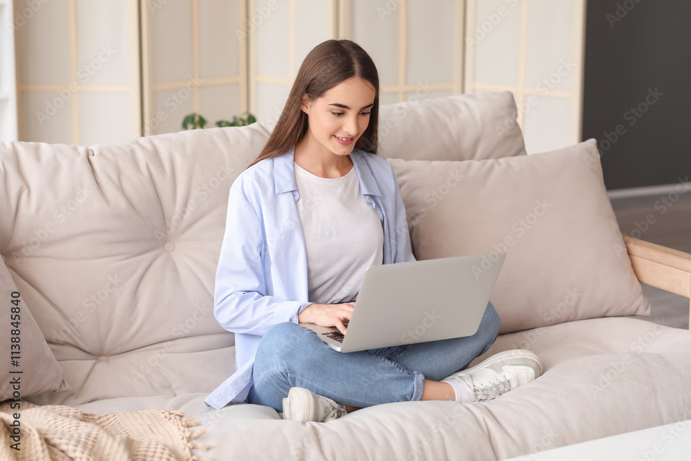 Beautiful young happy woman with laptop sitting on sofa at home Beautiful young happy woman with laptop sitting on sofa at home