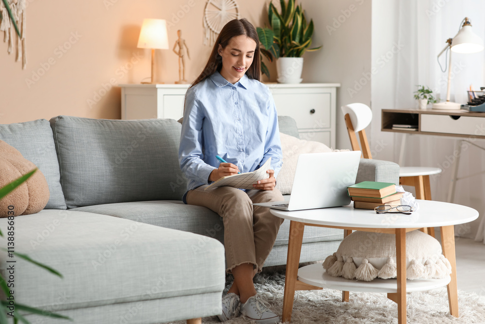 Beautiful happy female writer with laptop and notebook sitting on sofa at home Beautiful happy female writer with laptop and notebook sitting on sofa at home