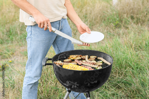 Young man cooking food on g...