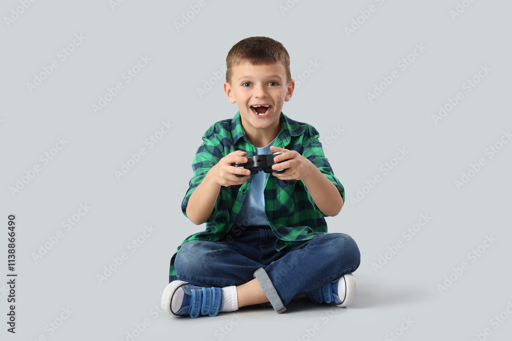 Cute little boy playing video game on light background Cute little boy playing video game on light background