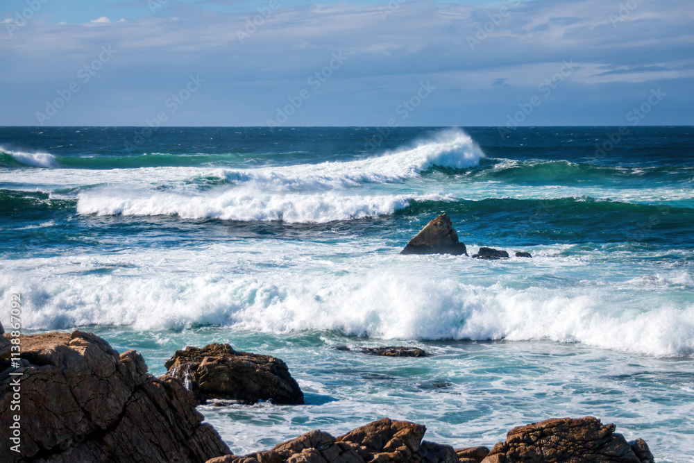 Scenic view of Pacific Ocean waves at the coast seen from Spanish Bay Vista Point, Del Monte Forest, California, USA against blue sky with clouds