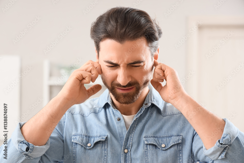 Young man suffering from ear pain at home, closeup Young man suffering from ear pain at home, closeup
