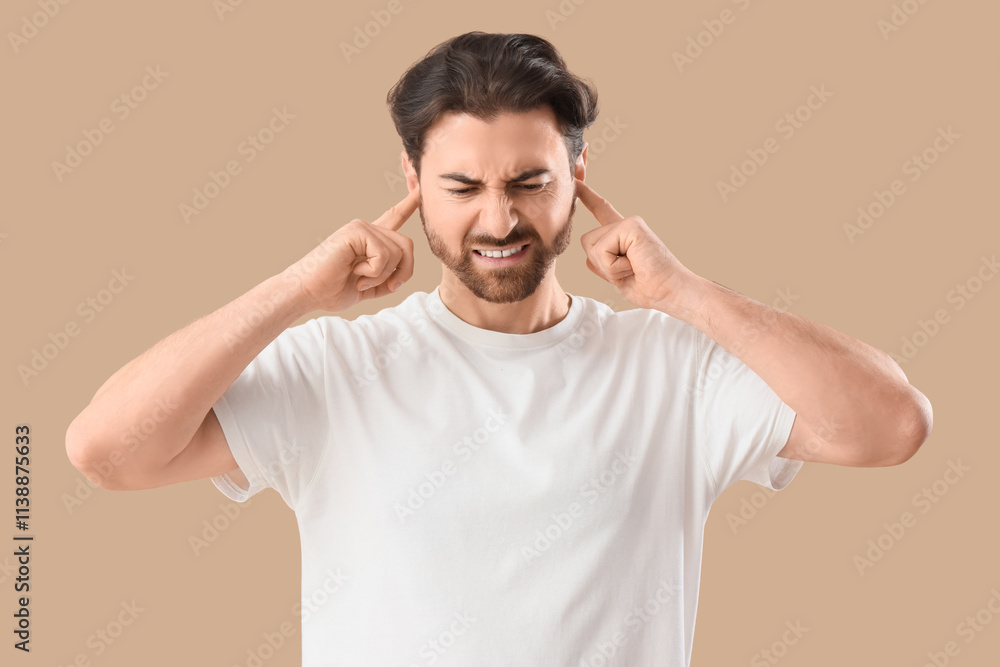 Young man with hearing problem covering his ears on beige background Young man with hearing problem covering his ears on beige background