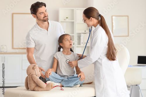 Female pediatrician with stethoscope listening to girl and father in clinic photo