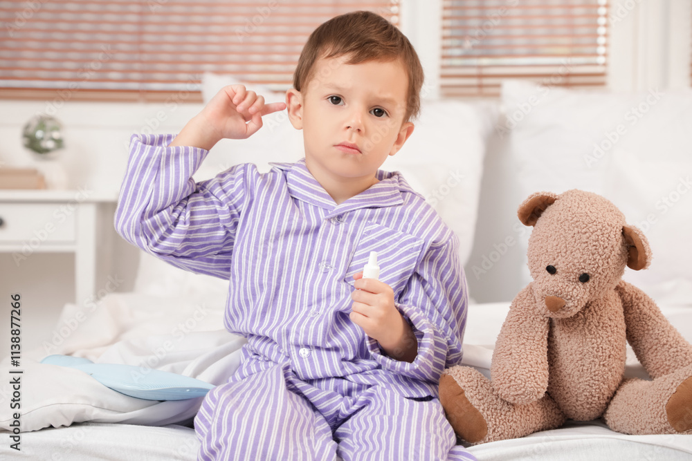 Little boy with drops and toy bear suffering from ear pain in bedroom Little boy with drops and toy bear suffering from ear pain in bedroom