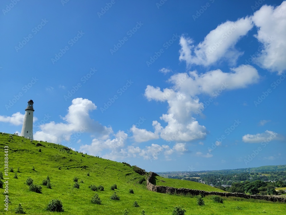 Lighthouse Monument on Green Hill with Blue Sky and White Clouds