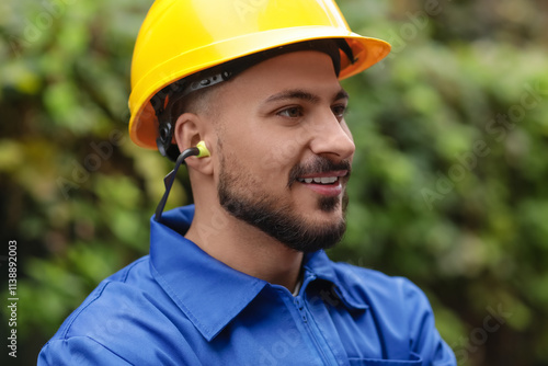 Canvas Print Male builder in hardhat with earplugs outdoors, closeup