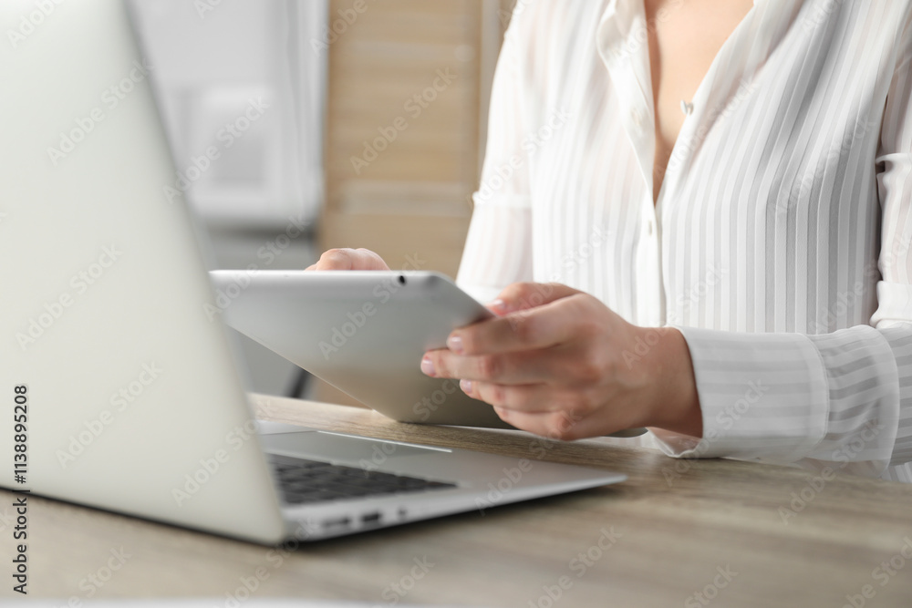 Businesswoman using tablet at wooden table indoors, closeup. Modern technology Businesswoman using tablet at wooden table indoors, closeup. Modern technology