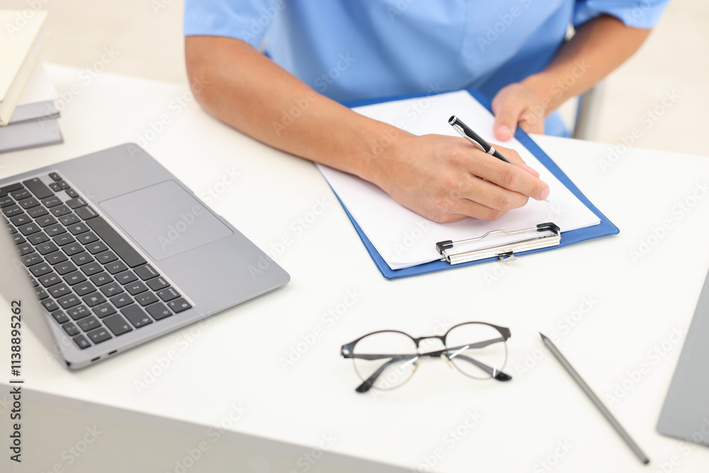 Fototapeta premium Medical student taking notes while studying at table indoors, closeup