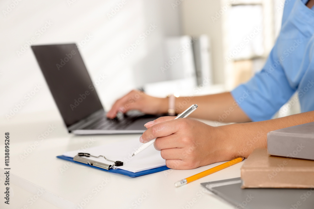 Medical student studying with laptop at table indoors, closeup Medical student studying with laptop at table indoors, closeup