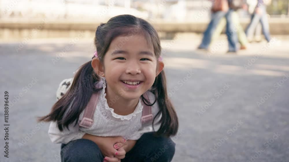Little girl smiling and crouching in a park Little girl smiling and crouching in a park