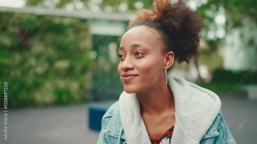 Clouse-up of nice young African American woman with ponytail in denim jacket looking around. Slow motion Clouse-up of nice young African American woman with ponytail in denim jacket looking around. Slow motion