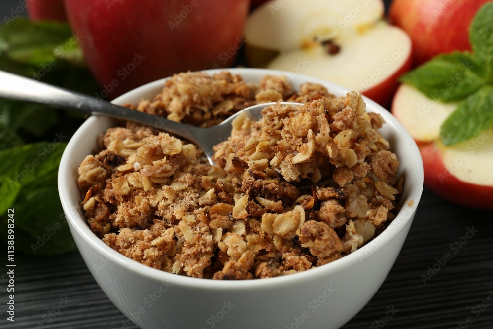 Delicious apple crisp in bowl, fresh fruits and mint on black textured table, closeup Delicious apple crisp in bowl, fresh fruits and mint on black textured table, closeup