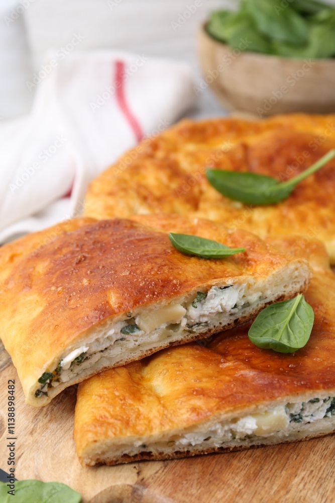 Pieces of tasty calzone with basil and cheese on table, closeup Pieces of tasty calzone with basil and cheese on table, closeup
