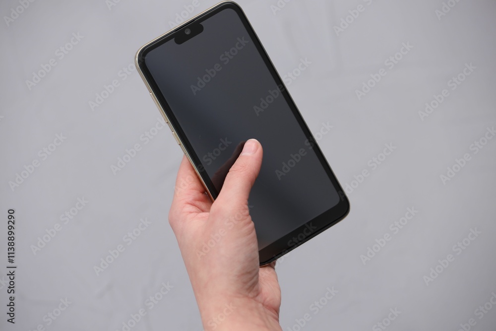 Woman using smartphone with blank screen on grey background, closeup Woman using smartphone with blank screen on grey background, closeup
