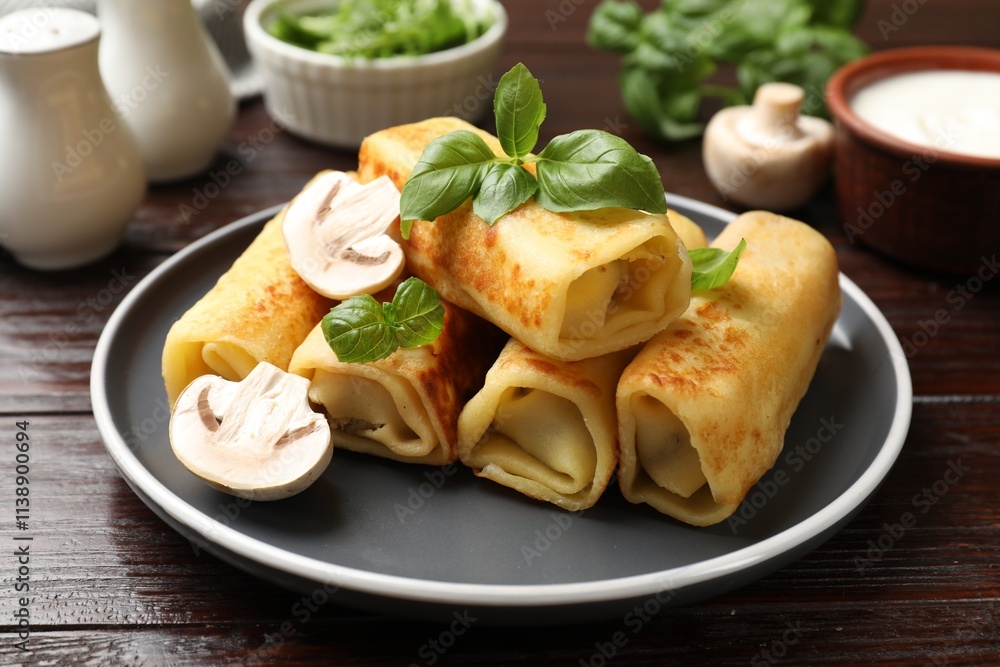 Delicious rolled crepes with mushrooms and basil on wooden table, closeup Delicious rolled crepes with mushrooms and basil on wooden table, closeup
