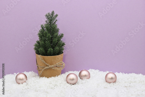 Christmas and New Year card with tree and decoration of Christmas balls and snow on pink-purple background