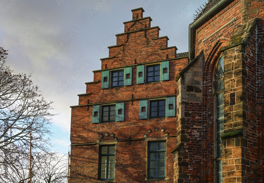 Fototapeta premium Historic building at the Martini church in Bremen, Germany in red brick architecture with stepped gable and wooden shutters, cloudy sky