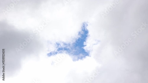 A Serene View Of A Vibrant Blue Sky Seen Through An Opening In Fluffy White Clouds, Offering A Sense Of Peace And Tranquility.