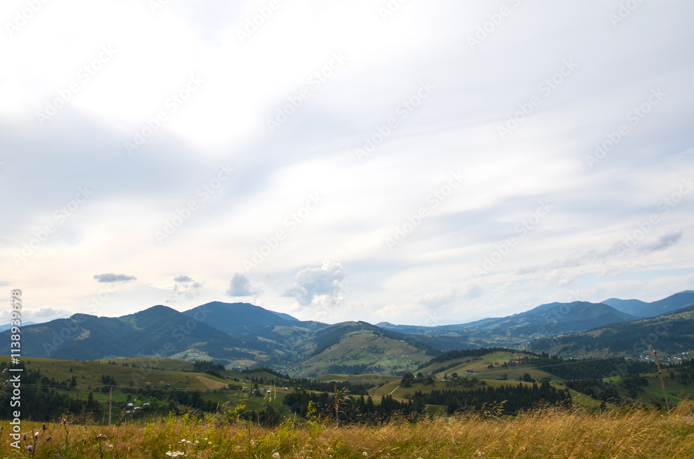 Serene view of rolling hills and distant mountains beneath an expansive sky filled with soft clouds. Perfect for evoking peace and tranquility in natural and rural settings. Carpathians, Ukraine Serene view of rolling hills and distant mountains beneath an expansive sky filled with soft clouds. Perfect for evoking peace and tranquility in natural and rural settings. Carpathians, Ukraine