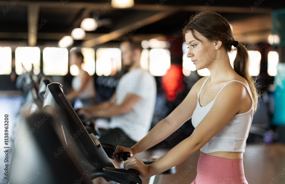 Young woman in sportswear training on exercise bike in gym Young woman in sportswear training on exercise bike in gym