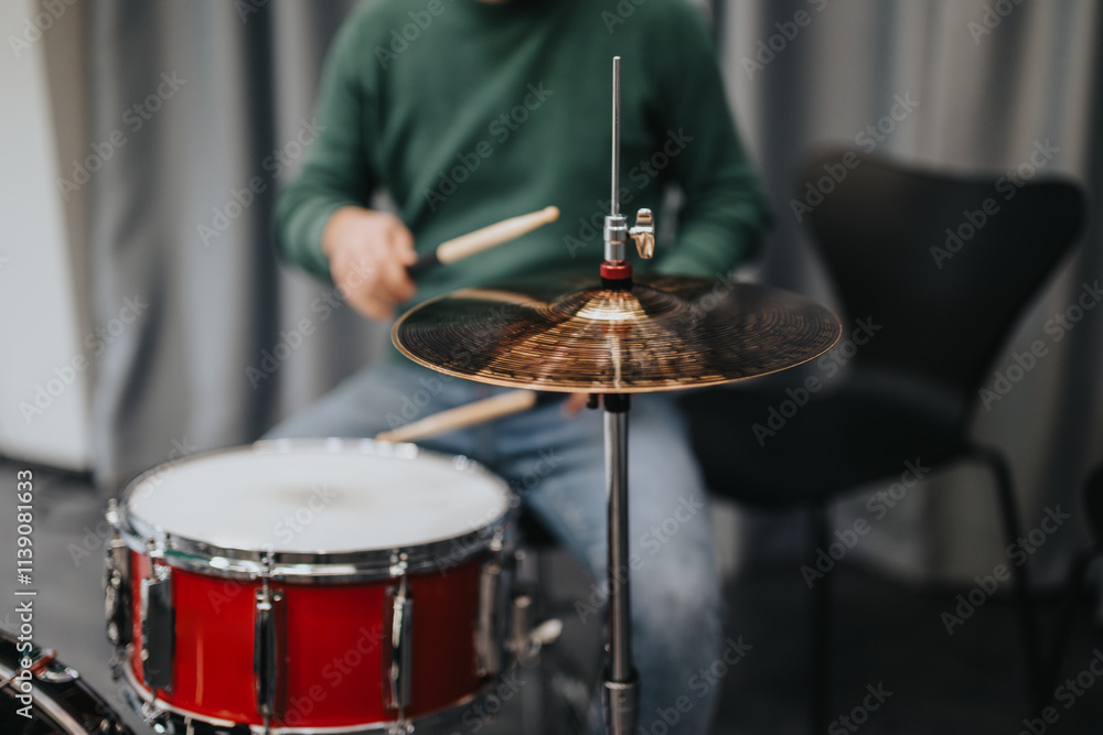 Fototapeta premium A drummer focuses on playing a cymbal during a practice session. The image captures the dynamics of drumming and the musician's skill, highlighting the art of percussion in music.
