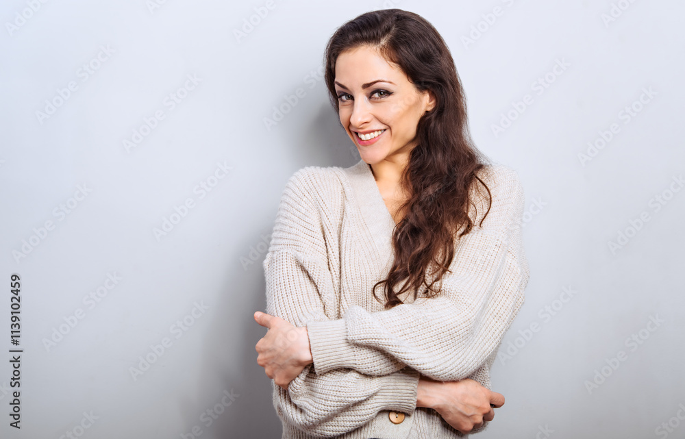 Happy smiling beautiful woman hugging herself in warm winter warm cozy cardigan with natural emotional face. Closeup real humal studio portrait Happy smiling beautiful woman hugging herself in warm winter warm cozy cardigan with natural emotional face. Closeup real humal studio portrait